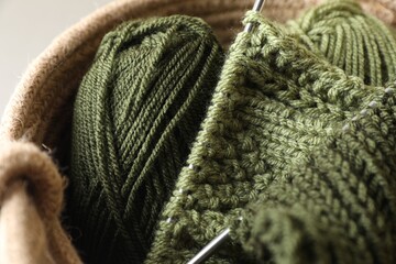 Fototapeta na wymiar Green knitting, needles and soft yarns on light background, closeup