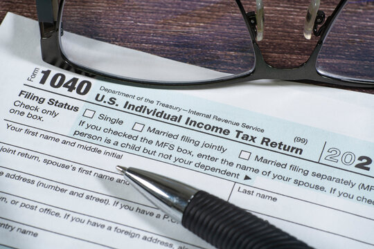 Close up of upper left corner of IRS form 1040 with eyeglasses and pen.