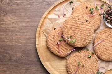 Fototapeta premium Tasty vegan cutlets with breadcrumbs on wooden table, top view. Space for text