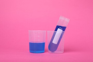 Beakers with test tube and liquid on bright pink background. Kids chemical experiment set