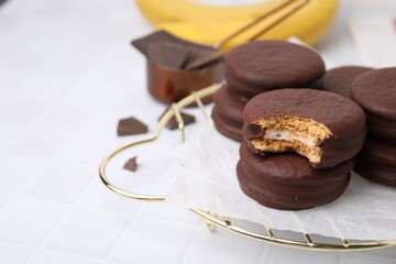 Tasty banana choco pies on white tiled table, closeup. Space for text