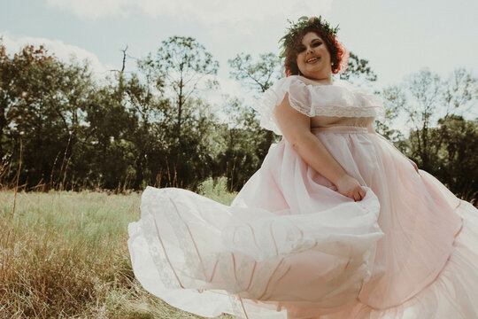plus size woman plays with dress in field