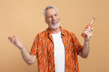 Portrait of smiling senior man wearing stylish orange shirt and white t shirt holding lemonade isolated on beige background. Positive lifestyle, summer concept