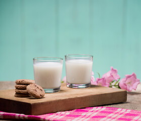 Glasses of milk and cookies on cutting board. Two glasses full of fresh milk.