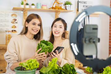 Vlogger young women blogger and influencer apron showing eat salad of healthy food for health care. team using smart mobile phone live online selling food replacement fit body for weight lose.