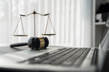 Symbolizing justice and legal authority, golden balanced scale and gavel on desk with laptop in law office background, reflecting concept of equality and fair judgment by lawyer and judge. equility