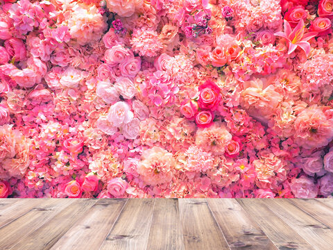Wood table top over artificial pink flowers bouquet background.