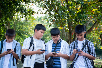 Young asian boys using mobile phone while walking homes afterschool together, soft focus, concept...