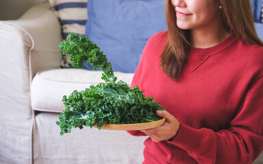 Closeup image of a young woman holding and picking up kale leaves