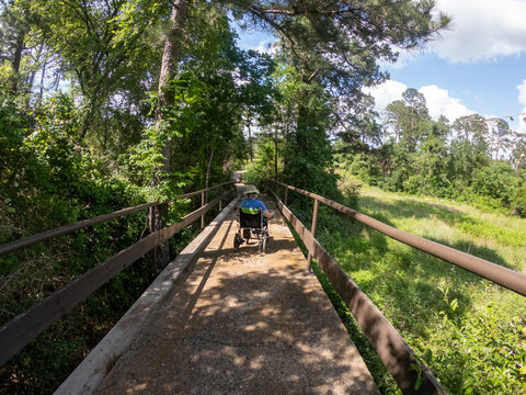 Person in a wheelchair on the 01' 9 Loop trail at the bridge at Bastrop State Park Texas
