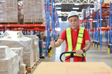 Warehouse workers man with hardhats and reflective jackets pulling a pallet truck and taking or upload with large box package to shelf in retail warehouse logistics, distribution center