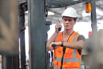 Young architect men or forklift driver sitting in vehicle with confident while looking at camera at heavy industry manufacturing factory.