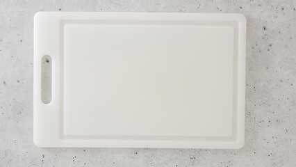 White plastic cutting board close-up on a gray stone kitchen countertop, flat lay, copy space