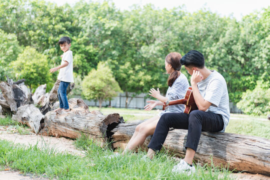 Image of young Asian family playing together at park