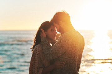 Sunset, beach and couple touching face for relaxing, bonding and quality time on romantic date. Nature, love and man and woman embrace for anniversary or honeymoon on holiday, weekend and vacation