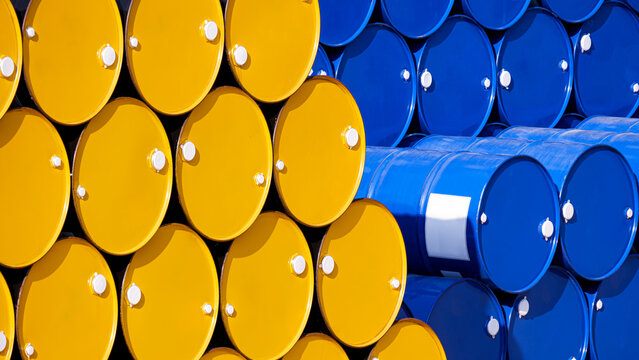 Background of many yellow and blue 200 liter oil drums stacked in perspective side view