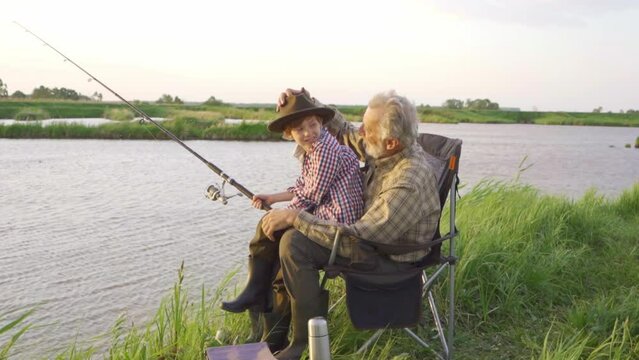 old bearded garndfather takes care of his happy grandson Generation, summer holidays concept. Slow motion Happiness pleasant unforgettable moments Love, little boy is happy as grandpa took him fishing