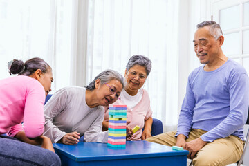 Senior people playing a wooden block tower, risk and strategy of project management. Concept of business risk with domino blocks. Older People playing jenga block removal game on table at home