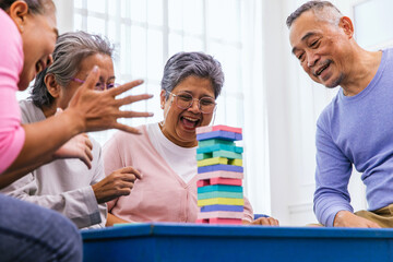 Senior people playing a wooden block tower, risk and strategy of project management. Concept of business risk with domino blocks. Older People playing jenga block removal game on table at home