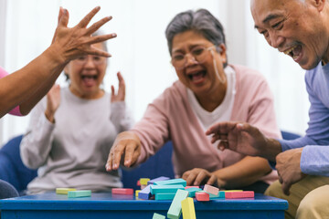 Senior people playing a wooden block tower, risk and strategy of project management. Concept of business risk with domino blocks. Older People playing jenga block removal game on table at home