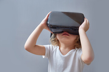 A curly-haired child looks into virtual reality glasses.