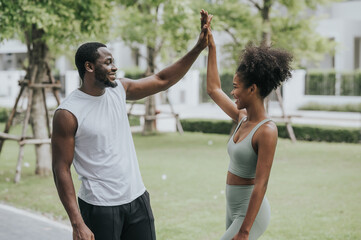 Happy smiling healthy couple in fitness wear giving high five outdoor at the park