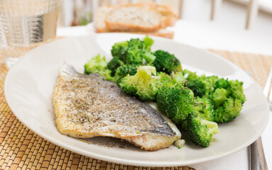 dish of fried dorado fish fillet with boiled broccoli