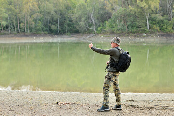 hombre adulto con una mochila negra haciendo fotos y shelfies en un bosque con un lago en Marbella España