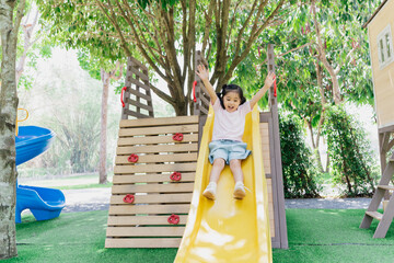 Cute asian girl smile play on school or kindergarten yard or playground. Healthy summer activity for children. Little asian girl climbing outdoors at playground. Child playing on outdoor playground.
