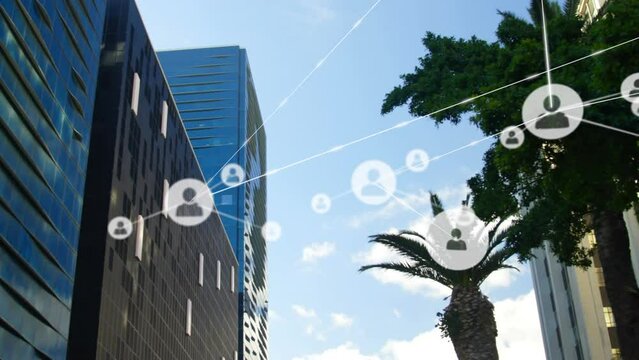 Animation of network of profile icons against low angle view of tall buildings and blue sky