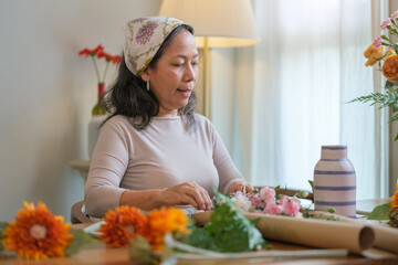 Happy senior woman and adult daughter making bouquet, decorations and arrangements flower in cozy living room.