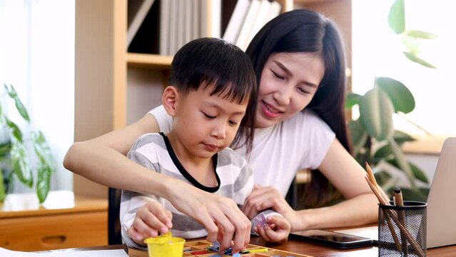 Young beautiful Asian single mother and son playing alphabet games with plastic toys into the word with anxiously for improve mental health and memory, learning concept, weekend activity .