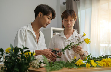 Serene homosexual couple enjoying leisure weekend time at home, making bouquet of flowers at table in living room.