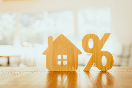 Percentage and house sign symbol icon wooden on wood table. Concepts of home interest, real estate, investing in inflation.	
