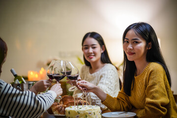 Cheerful friends enjoying home Birthday holiday party. Asian Friends cheering drinking red wine celebrating Christmas or New Year party