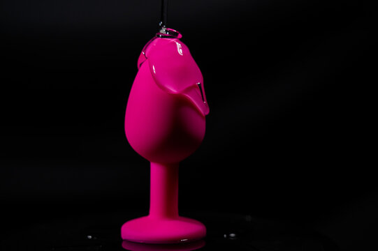Pink anal plug in intimate lubricant on a black background. 