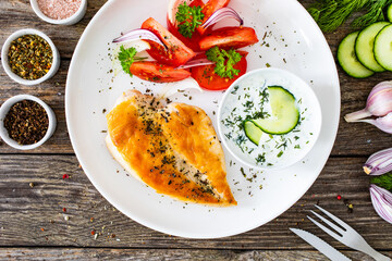 Seared chicken breast and tzatziki on wooden table