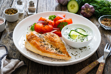 Seared chicken breast and tzatziki on wooden table