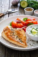 Seared chicken breast and tzatziki on wooden table