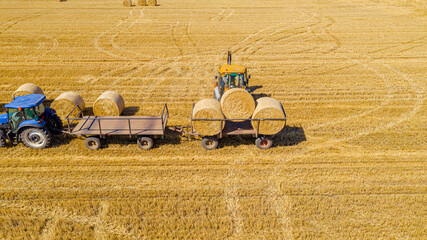 Aerial view of agricultural field, collecting round bales of straw