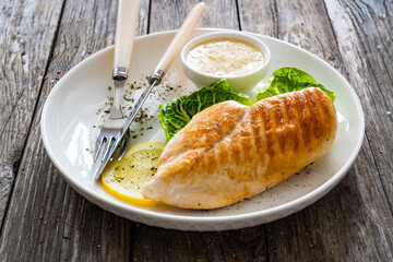 Barbecued chicken breast and greens on wooden table
