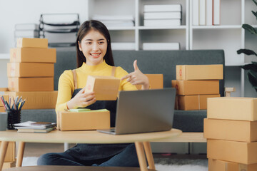 Obraz na płótnie Canvas tarting Small business entrepreneur SME freelance,Portrait young woman working at home office, BOX,smartphone,laptop, online, marketing, packaging, delivery, SME, e-commerce concept