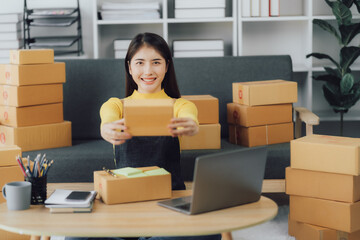tarting Small business entrepreneur SME freelance,Portrait young woman working at home office, BOX,smartphone,laptop, online, marketing, packaging, delivery, SME, e-commerce concept