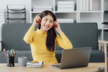 Beautiful young asian woman with headphones relaxing on the sofa. She is listening to music using smartphone . Chill out and leisure concept