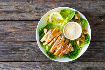 Caesar salad - fried chicken breast and vegetables on wooden table
 - obrazy, fototapety, plakaty