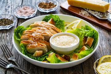 Caesar salad - fried chicken breast and vegetables on wooden table

