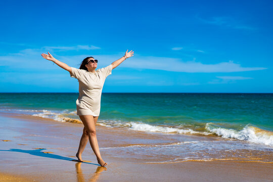 Beautiful woman walking on sunny beach
