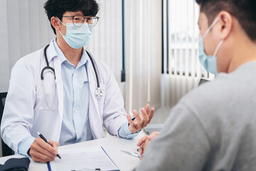 Male doctor in medical face mask is explaining about symptoms of