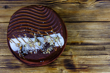 Ceramic plate with chocolate cake on a wooden table. Top view