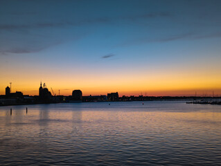 Sonnenuntergang über der Silhouette von Stralsund an. Sicht vom Strelasund. Nahe der Insel Rügen und der Ostsee.